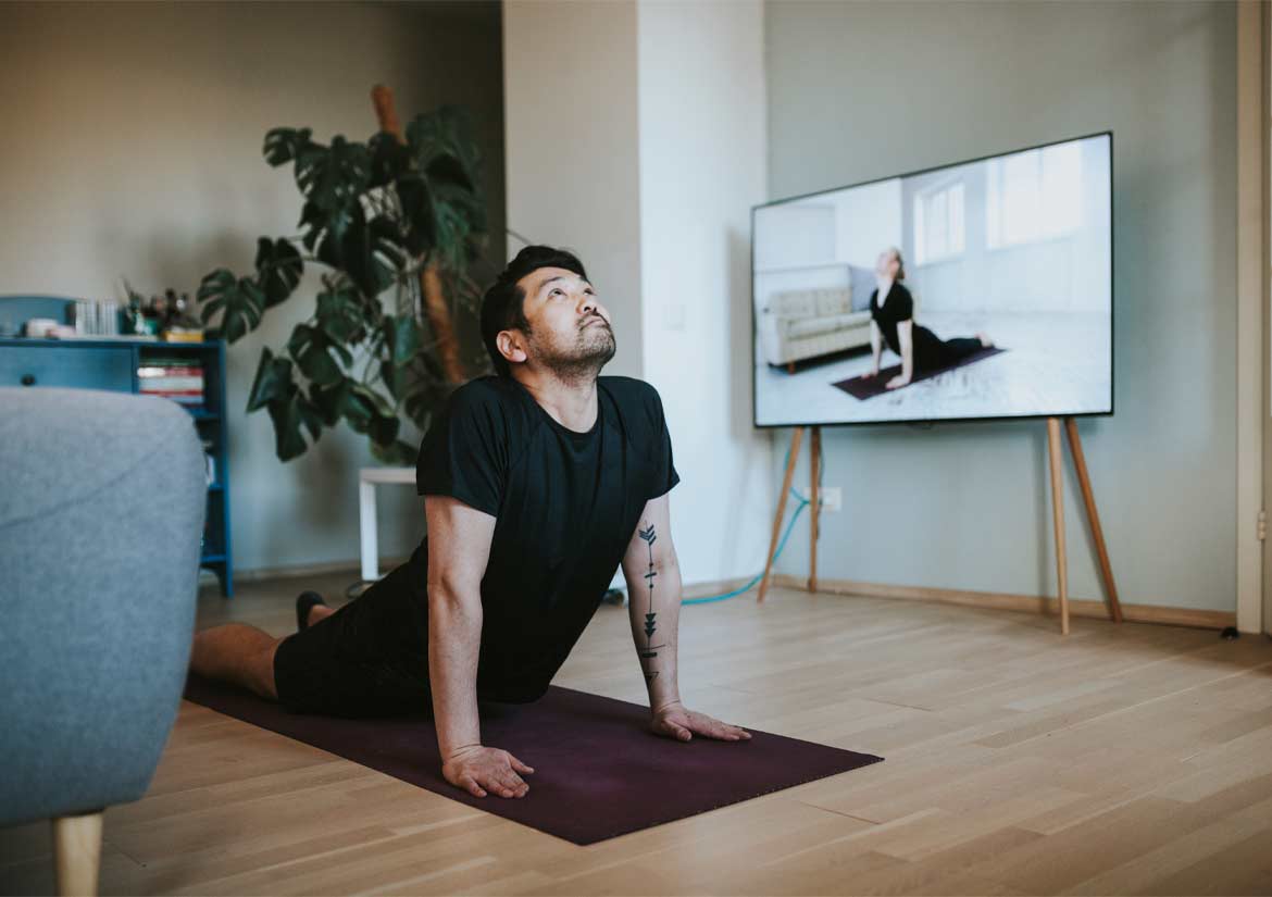 Man doing yoga on floor next to television