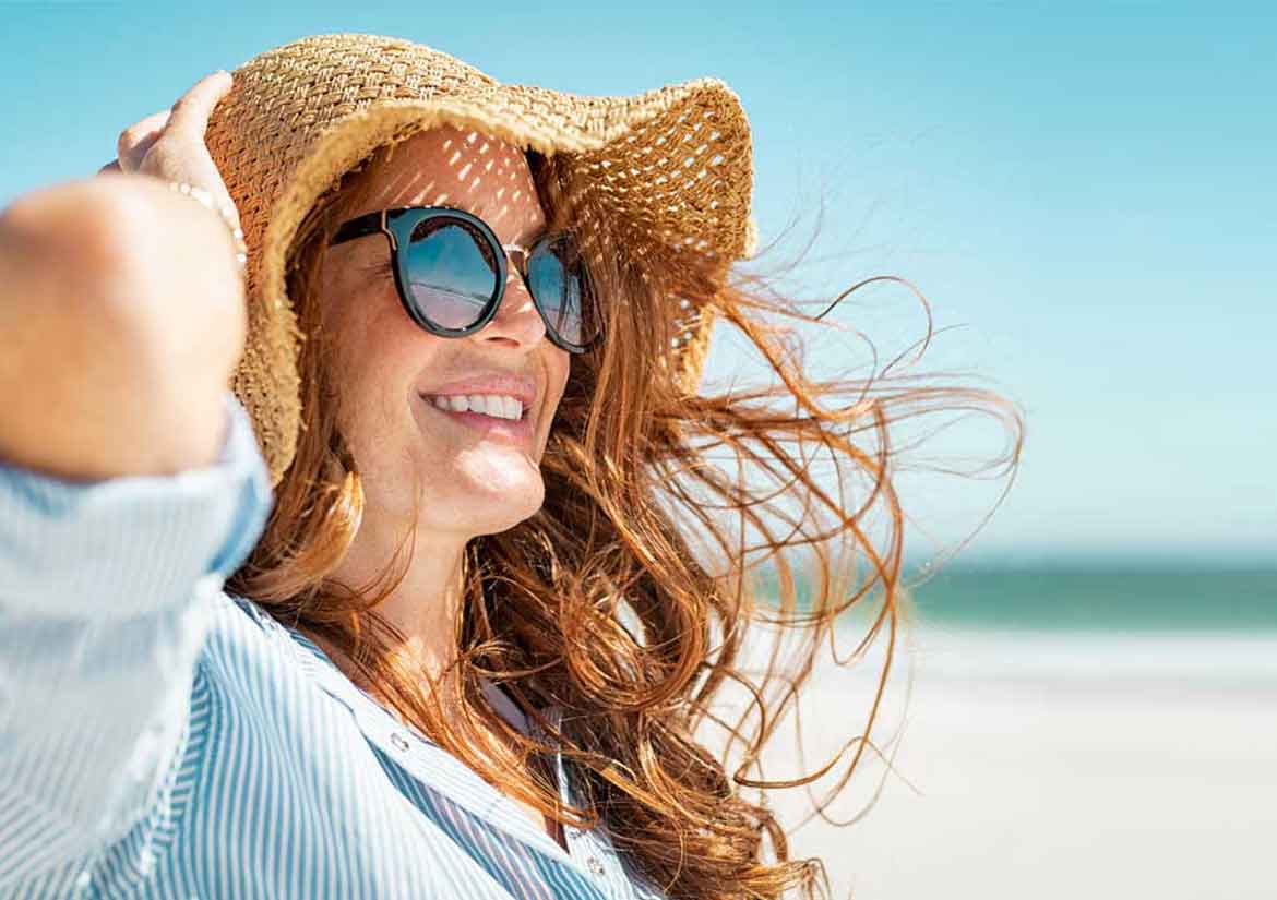 Woman at beach smiling towards the sun