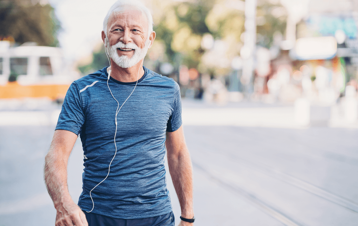 Older man wearing earphones walking outside