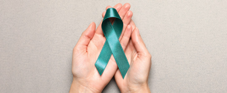Hand holding green ribbon for cervical cancer awareness month