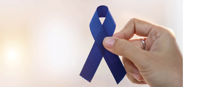 Hand holding dark blue ribbon for colorectal cancer awareness month
