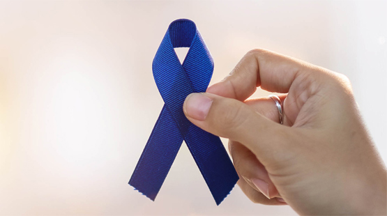 Hand holding blue ribbon for colorectal cancer awareness