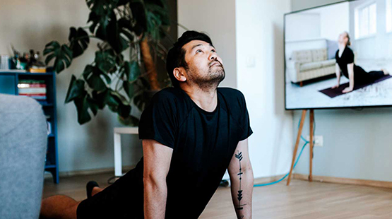 Man practicing yoga with tv instructor