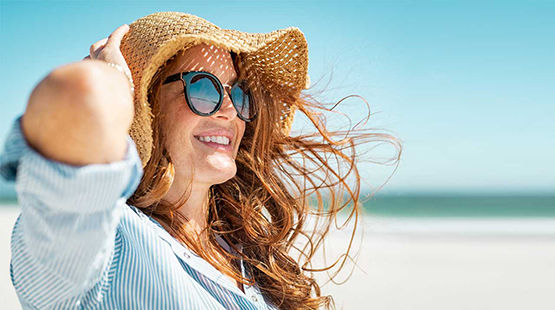 Woman wearing sunhat and smiling at beach
